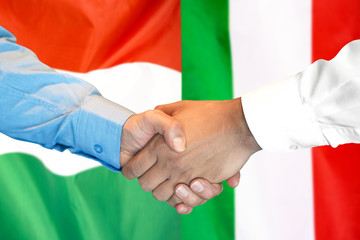 handshake on Hungary and Italy flag background.