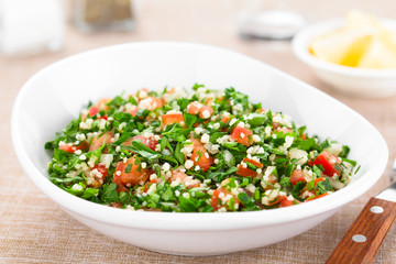 Fresh vegan Tabbouleh salad made of tomato, parsley, onion and couscous in bowl (Selective Focus,...