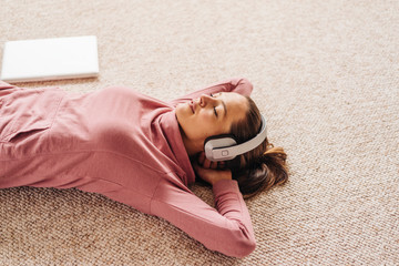 Woman lying on carpet wearing headphones