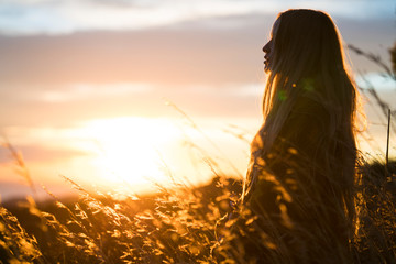 Side view of woman standing in field during sunset