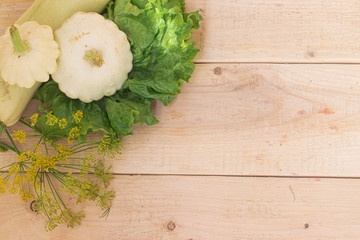 Homemade vegetables. Squash Squash white and lettuce on a wooden background. Green harvest on wooden background. Courgettes on a wooden background. Healthy food. Organic Products