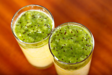 Glasses with pineapple smoothies and kiwi on the table.
