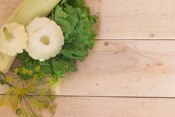 Homemade vegetables. Squash Squash white and lettuce on a wooden background. Green harvest on wooden background. Courgettes on a wooden background. Healthy food. Organic Products