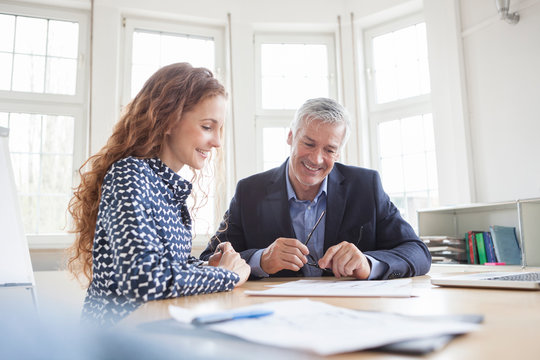 Businessman and woman at desk discussing plans