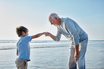 Grandfather giving grandson a fist bump on the beach