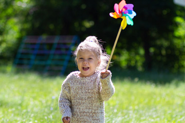 Child with Pinwheel in the summer park looking at camera