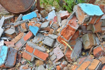 Pile of construction waste with old broken red bricks and broken boards. Rubbish from a ruined house with bricks pieces and old timber. Junk yard outdoor. Old building materials polluting environment