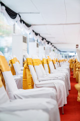 Temporary Air Conditioner indoor tent for outdoor event in the day. Inside Tents has red carpet and a lot of chair covered by white cloth and golde ribbon on it.