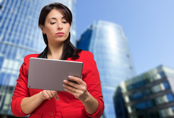 Woman using a tablet outdoor in a modern city setting
