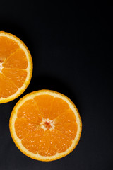 Orange slice on black background, top view