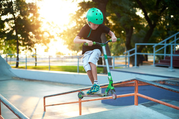 A boy on a scooter and in protective helmet do incredible stunts in skate park. Extreme jump. The...