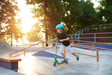 A boy on a scooter and in protective helmet do incredible stunts in skate park. Extreme jump. The...