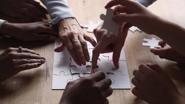 Closeup view multi-ethnic people connecting pieces of puzzle jigsaw