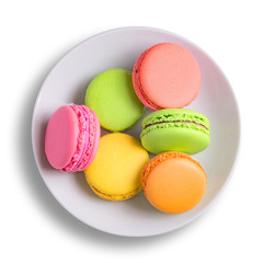 Pink, yellow, green macaroons cakes on a white plate. View from above