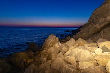 The sea wave hits the stones at sunset near the coast of the Holy Mount Athos