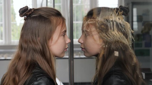 Teenager cute girl makes draw sketches in graphic tablet of animal skeletons in museum of nature as part of school task of biology
