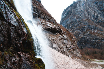 Small cliffy mountain spring waterfall in Abkhazia. Craggy ridge cliff with water bursts. Cold water rocky mountains of waterfall. Rock mountains falling stream.