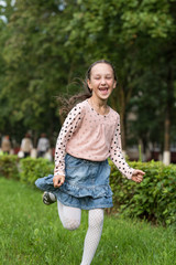 Little cheerful girl running through the grass.