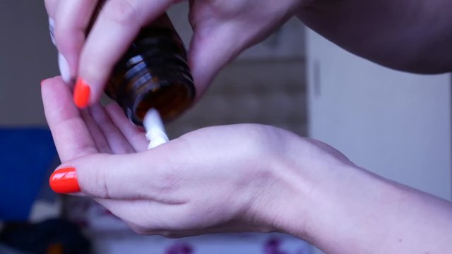 Young woman with bright manicure overdosing pills to commit suicide in the bedroom. Depressed woman committing suicide by taking a lethal dose of pills. Medication in hand.