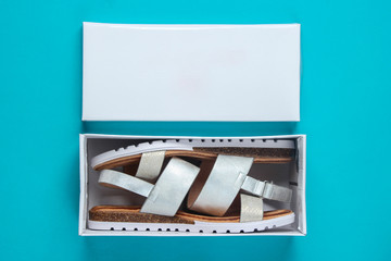 New women's leather sandals in a box on  blue background. Top view.