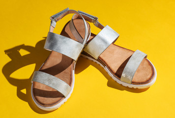 Stylish women's sandals on a yellow background. Summer footwear