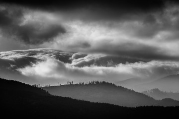 Fototapeta premium Amazing Carpathian landscape of misty mountain hills and cloudy sky in black and white. Ukraine.