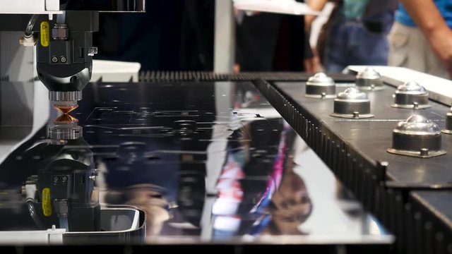 Industrial laser machine cutting metal, robotic mechanism sample at the international exhibition, technology concept. Media. Flat sheet of metal steel being cut with sparkles.