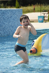 Little boy play swimming and playing in the pool. Cheerful child play in the swimming pool
