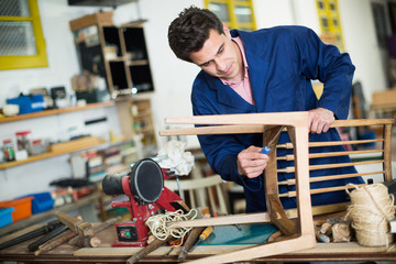 Man carpenter in furniture repair workshop