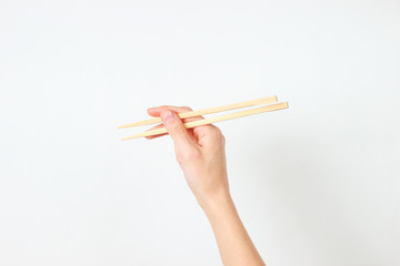 Female hand hold chopsticks on white background. Minimalistic food concept. Top view