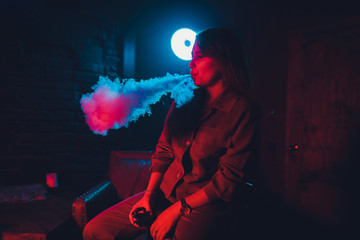 woman smokes a e-cigarette lying on the bed in the room. Smoker's concept Vaping.