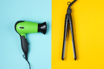 Minimalistic beauty and fashion still life. Hair dryer, hair straightener on colored pastel background. Top view, flat lay
