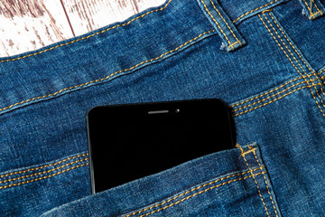 black smartphone sticking out of his jeans pocket