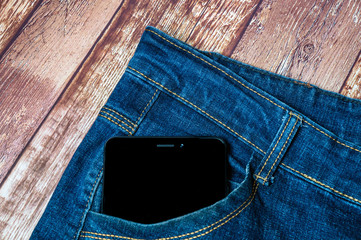 black smartphone sticking out of his jeans pocket