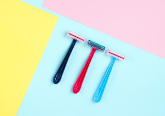 Minimalistic beauty concept. Epilation. Plastic colored razors on pastel background. Top view