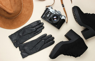 Women's fashionable autumn accessories, shoes and retro film camera on beige background. Top view travel, vacation concept. Flat lay