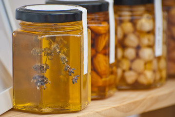 Jar of natural honey on a wooden stand. Homemade honey with sprigs of lavender.
