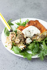Pie with liver, egg and dill filling on a white plate with sauce. Healthy nutrition lunch or dinner.
