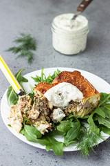 Pie with liver, egg and dill filling on a white plate with sauce. Healthy nutrition lunch or dinner.