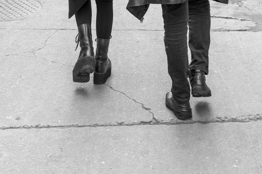 Street photograph with detail of a gothic couple walking with black clothes. Cracked floor. Saara, Rio de Janeiro, Brazil. 2019