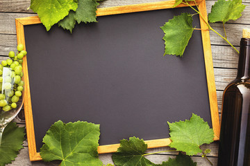 bottle of wine with a glass and grapes on a wooden table with copy space, top view. Concept on the...