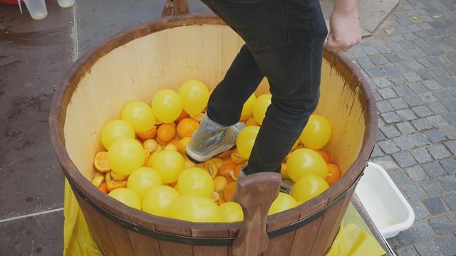 men's feet trampled citrus into a wooden vat for juicing. sunny summer day outdoors