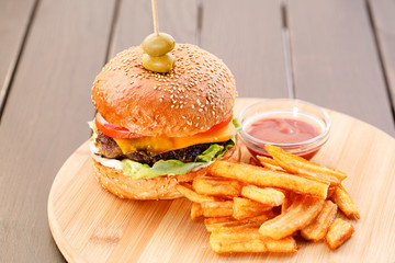 Juicy , tasty , healthy hamburger with fried potato on wooden plate , wood background.