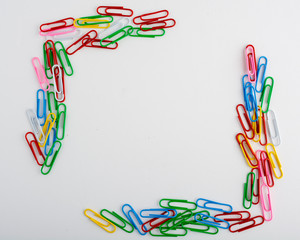 Multicolored paper clips arranged into a square frame on a white background.