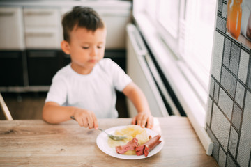 child in the kitchen eating sausage and mashed potatoes