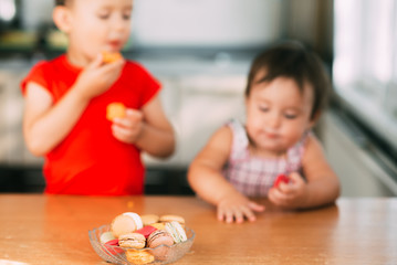 Obraz na płótnie Canvas Kids boy and girl eating cake macaroons. Having fun brother and sister