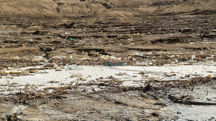 Dirty and muddy coastline of famous Dead Sea, a lot of garbage around Dead Sea, extremely salt lake, Jordan