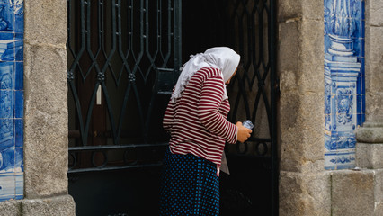 Portugal, Porto, July, 2019. Homeless beggar woman standing outdoors near the curch and asking for...