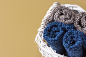 Folded rolled pure cotton terry washcloth towels in wicker basket on olive green bathroom wall background. Zero waste reusable eco friendly materials face body care concept