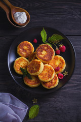 Cottage cheese pancakes on black plate. Syrniki with sour cream